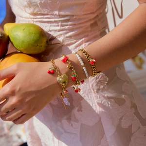 Layered gold chain bracelets with cherry, strawberry, and pearl charms for women