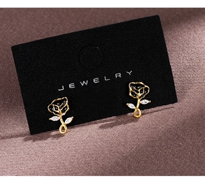 Macro detail of French retro black rose earrings with gold stems and zircon leaves