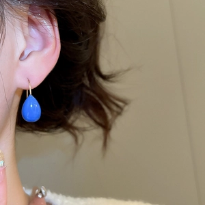 Vue détaillée de boucles d'oreilles gouttes bleues avec crochets dorés sur modèle