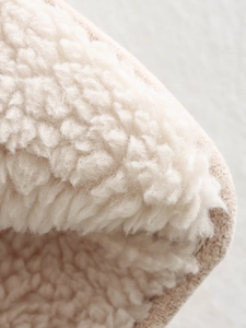 Macro shot of soft cream-colored sherpa fleece lining on a suede winter jacket