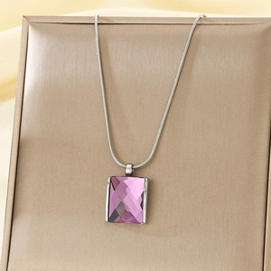 Detail of purple square crystal pendant on a silver snake chain over jewelry box