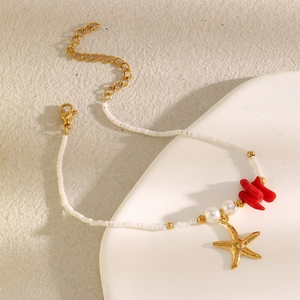 Macro detail of 18K gold starfish pendant on beaded ocean bracelet with coral accents