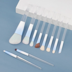 Set of 11 makeup brushes with clear handles and blue gradient ferrules on geometric stand