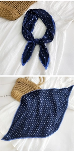 Dettaglio di un foulard di seta a pieghe con pois blu e bianchi e bordo a taglio ondulato