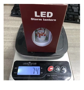 Weight measurement of a Christmas LED storm lantern showing 74g on a digital scale