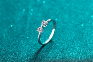Detail of silver S925 ring with double heart-shaped moissanite stones on a glitter background