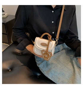 Chic beige mini crossbody bag with brown straps and a cute teddy bear charm