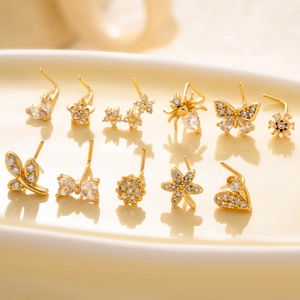 Set of 11 golden L-shaped nose studs with zircon butterfly, flower and spider designs