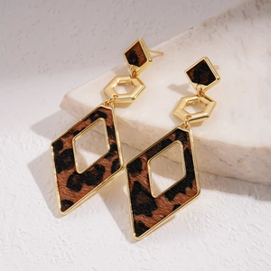 Macro shot of geometric gold earrings featuring leopard print and rhombus design