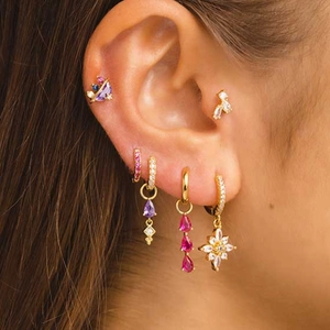 Close-up of golden S925 silver butterfly earrings set with purple and pink gemstones