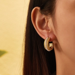 Close-up of gold-plated C-shape earrings with twisted metal and small pearls on model