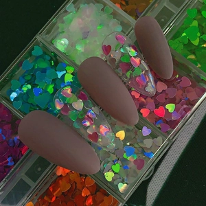 Detail view of colorful laser heart nail glitter sequins in a clear organizer box