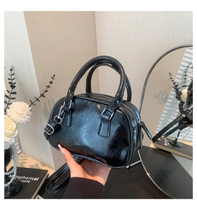 Detailed view of black patent leather bowling bag with silver hardware and glossy finish