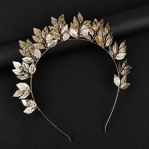 Detailed close-up of golden leaf headpiece with polished metal texture on black background