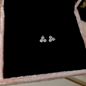 Detailed macro view of gold flower earrings with three diamonds in a pink jewelry box