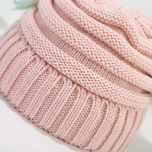 Close-up of soft pink knitted wool texture and ribbed cuff design on children winter hat