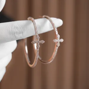 Chic silver hoop earrings with a zircon-paved cross pendant for a minimalist luxury look