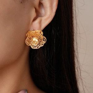 Makroaufnahme der doppellagigen goldenen Blumenohrringe mit filigraner Handwerkskunst