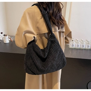 Detail of black corduroy hobo bag showing ribbed texture and wide shoulder strap