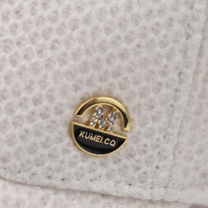 Close-up of scorpion baseball cap featuring an embroidered M logo with metallic detail