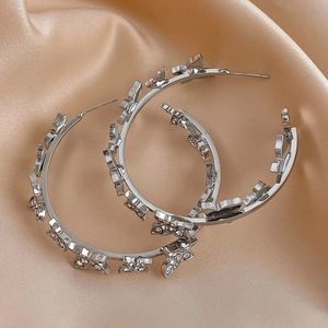 Detail of silver hoop earrings with butterfly motifs and sparkling rhinestones on silk