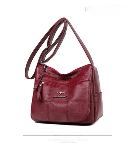 Detail of burgundy lychee leather bag with checkered stitching and multi-zipper pockets