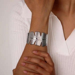 Close-up of textured silver stainless steel wide cuff bracelet worn on female wrist