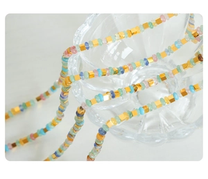 Vue macro de perles en pierre macaron avec intercalaires dorés sur verre ondulé