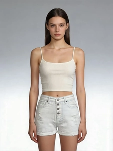 Close-up of high-waisted light blue denim shorts with ripped details and a white ribbed top