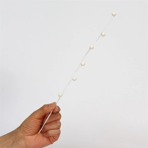 Detail of white artificial berry stem decorative branch held by hand on white background