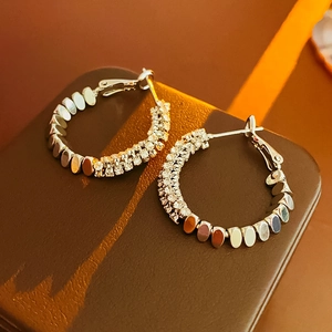 Detail of silver hoop earrings featuring cubic zirconia pavé and polished metal finish