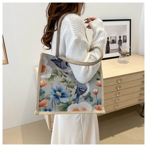 Detail shot of vintage floral bird pattern on linen tote bag held by a model