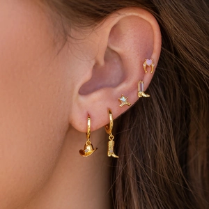 Detail showing western style gold earring set with boots, hats and sheriff star on model