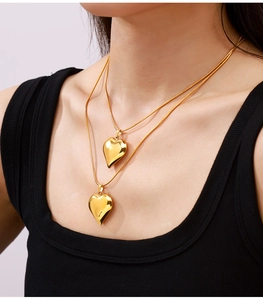 Close-up of golden heart pendant necklace on model with layered snake chain style