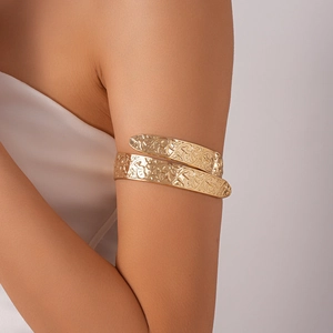 Detailed view of golden upper arm cuff with intricate floral and vine engraved textures