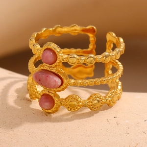 Makrodetail eines 18K vergoldeten dreischichtigen Rings mit drei rosa Edelsteinen und Perlen