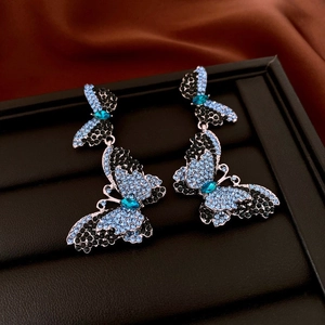Close-up of double butterfly drop earrings with black and blue sparkling rhinestones
