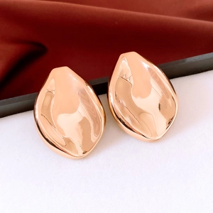Gros plan de boucles d'oreilles dorées polies en forme de feuille sur soie élégante