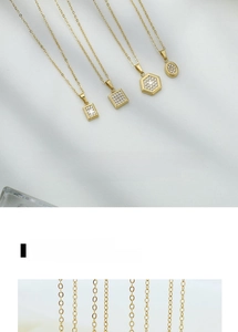 Detailed close-up of geometric gold necklaces with pave-set zircon pendants on fabric