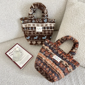 Close-up of cozy plush tote bags with snowflake and striped patterns on a white sofa