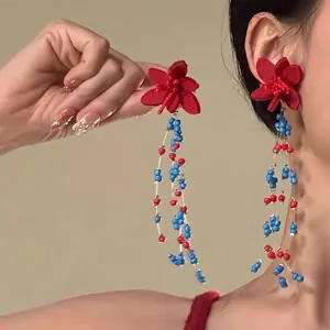 Detail of red flower beaded tassel earrings with blue bead strings for summer look