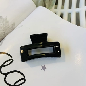 Glossy black rectangular hair claw clip placed on a stylish magazine background