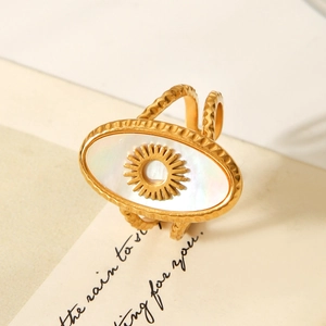 Macro shot of gold sunburst ring with white shell inlay on a poetic beige card