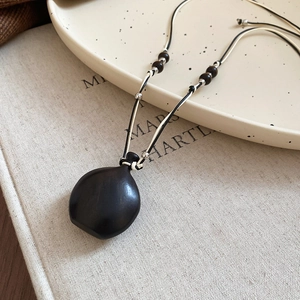 Handmade ethnic necklace with dark wood pendant and wax cord, minimalist bohemian style