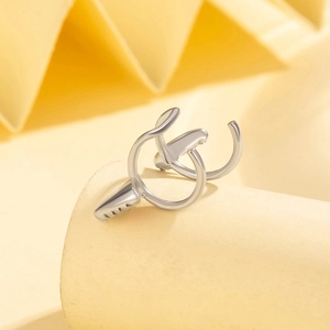 Silver cat ear cuff with zircon inlay and flowing streamlined design on a yellow background