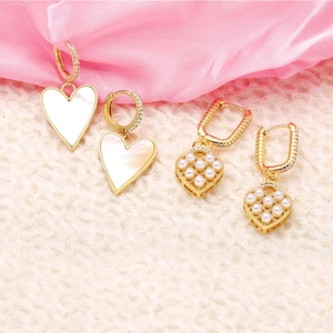 Golden heart earrings with pearls and crystals on soft pink silk and white fur background