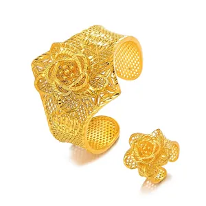Detail of gold hollow floral filigree bracelet and ring set with intricate rose texture