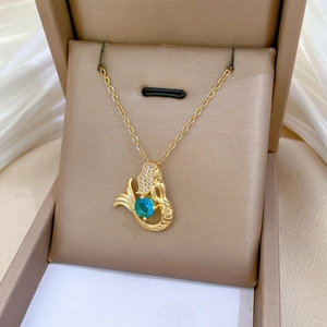 Detail of a golden mermaid pendant with a blue-green stone and white diamonds