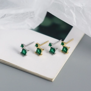 Macro detail of geometric square green zircon stud earrings in gold and silver finish