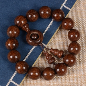Macro detail of sandalwood Buddhist prayer beads with gourd charms on a vintage book